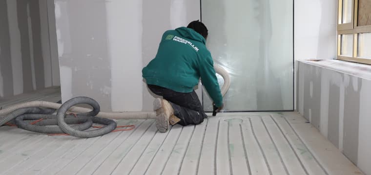 Monteur legt vloerverwarmingsbuizen in gefreesde sleuven